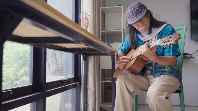亚洲老年男子喜欢在家里的客厅里弹吉他