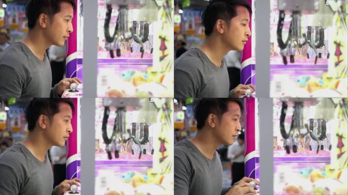 一名亚洲游客在日本街机上玩鹤爪游戏机