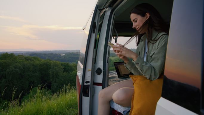 DL年轻女子在货车后部使用智能手机时欣赏风景