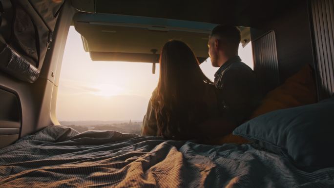 DL热爱的年轻夫妇喜欢从面包车后面欣赏日落的景色