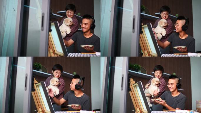一名亚洲中国青少年在家里客厅里画丙烯画，用耳机听音乐，而他的母亲则在沙发上用笔记本电脑和宠物玩具贵宾
