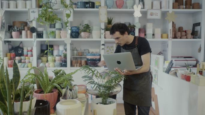 小企业主在他的植物学精品店使用笔记本电脑