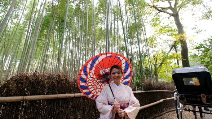 4K鹤拍：日本京都荒山和佐野竹林中，一位身着传统和服的亚洲女性与日本人力车合影，欢迎您来到日本