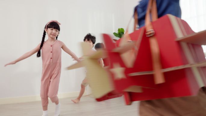 一名亚洲小学男孩穿着与真实飞机颜色和结构相似的纸飞机，和他微笑快乐的朋友们在教室里跑来跑去。与朋友共