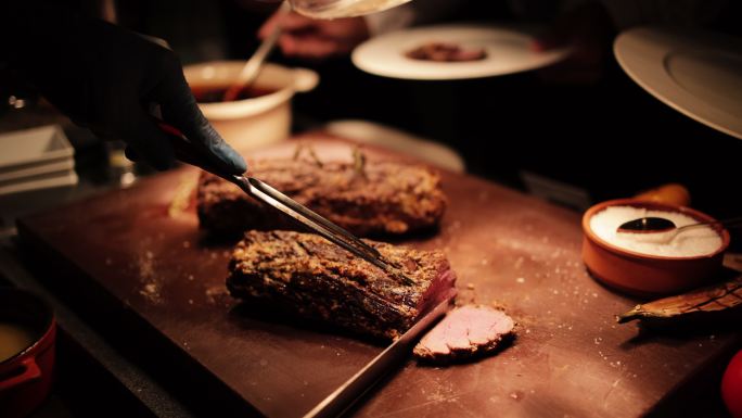 餐厅柜台上的烤肉。在餐厅用餐时吃肉。厨师正在切牛排片。