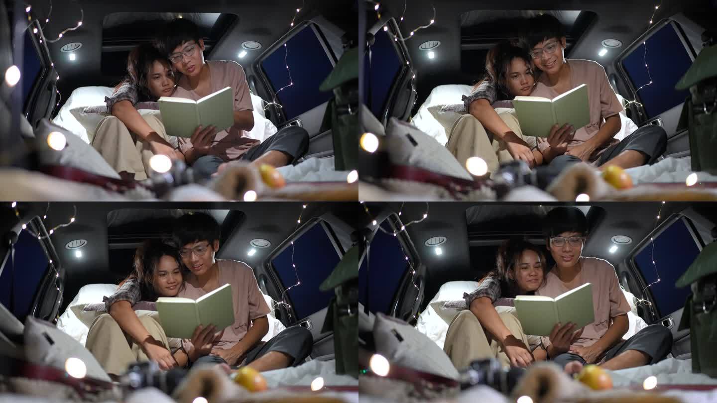 一对幸福的年轻夫妇在夜晚露营时，在一辆有灯光的汽车里一起看书