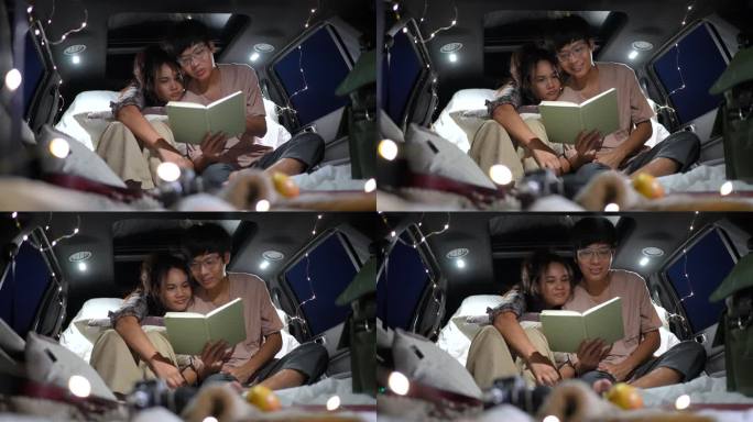 一对幸福的年轻夫妇在夜晚露营时，在一辆有灯光的汽车里一起看书