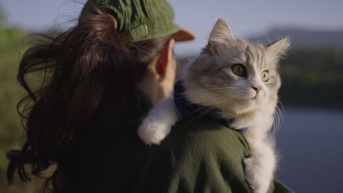 一个女人在外面肩上扛着一只猫