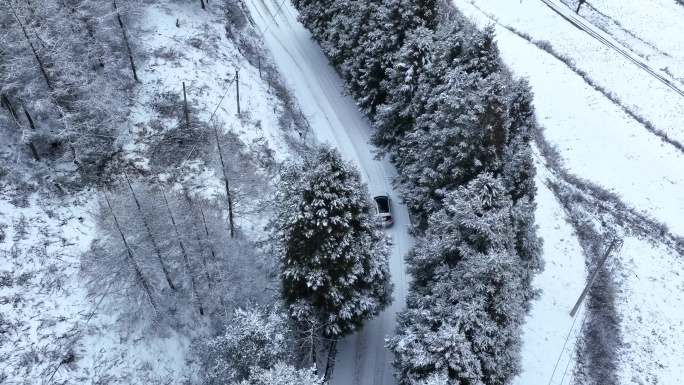 航拍车辆行驶在积雪覆盖的道路上4K