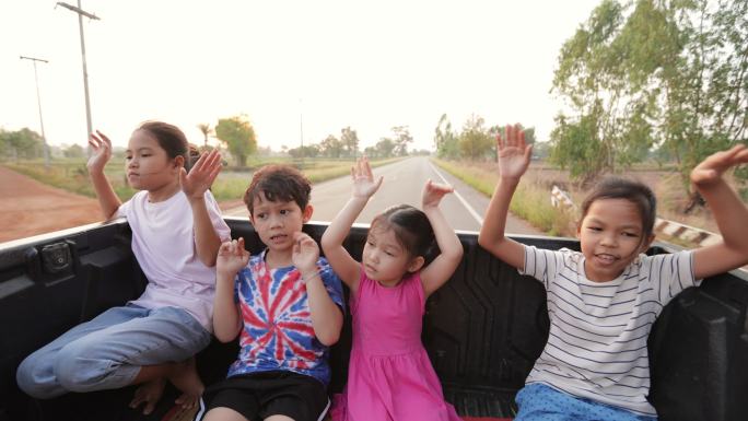 亚洲兄弟姐妹男孩和女孩在乡下旅行时一起坐在汽车后备箱里玩耍。童年和兄弟姐妹喜欢开车旅行。