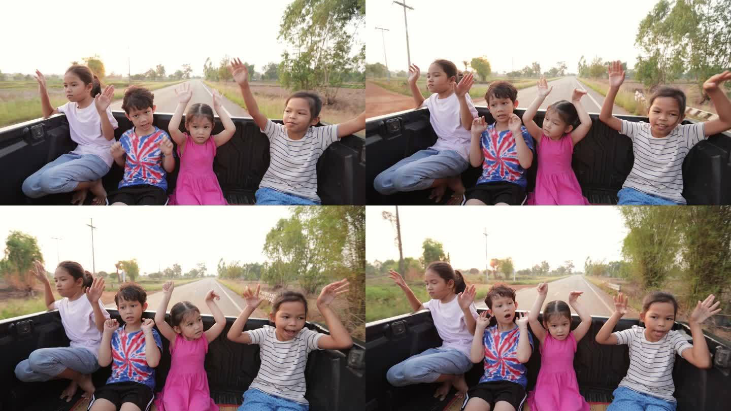 亚洲兄弟姐妹男孩和女孩在乡下旅行时一起坐在汽车后备箱里玩耍。童年和兄弟姐妹喜欢开车旅行。