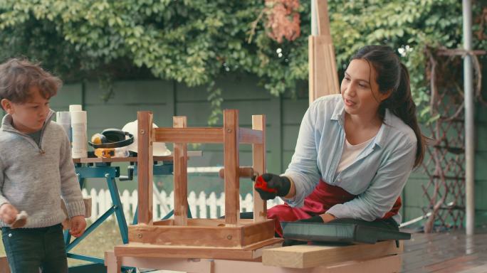 4k视频画面显示，一名年轻女子在家中与她可爱的儿子一起完成一个木制项目