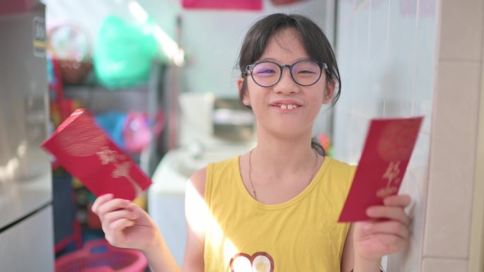 亚洲中国年轻女孩看着手机摄像头，用红包和橘子向爷爷奶奶祝贺中国新年