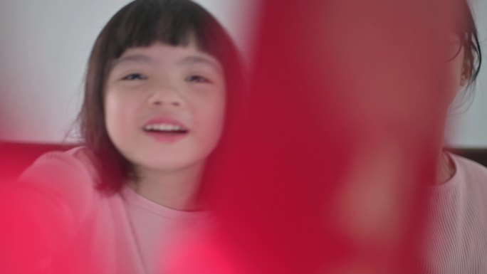 亚洲中国年轻女孩和她的妹妹看着笔记本电脑摄像头，用红包和橙色向祖父母问候中国的新年庆祝活动