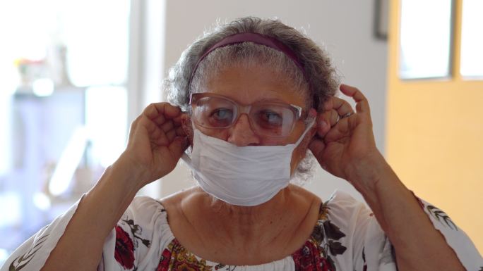 老年妇女在脸上戴防护口罩