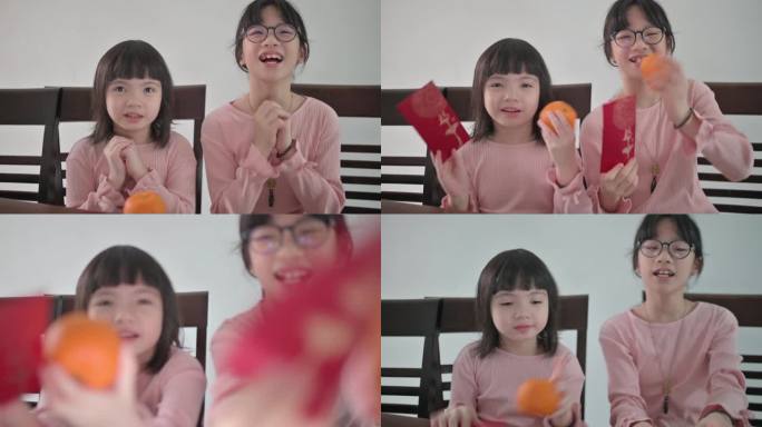 亚洲中国年轻女孩和她的妹妹看着笔记本电脑摄像头，用红包和橙色向祖父母问候中国的新年庆祝活动