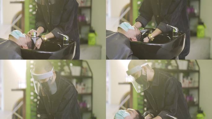 亚洲中国发型师，穿着防护服，在美发沙龙为顾客洗头