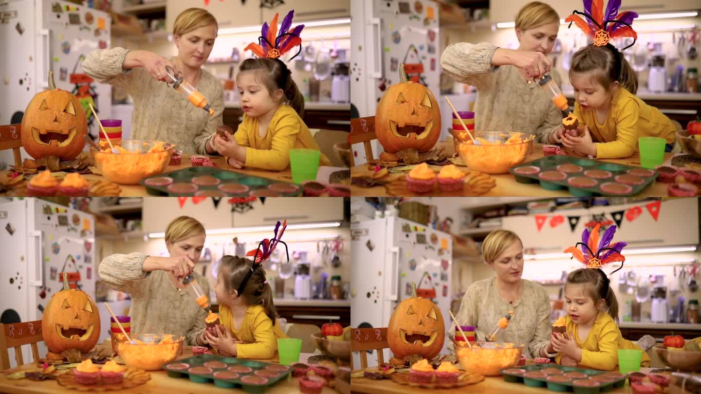 好奇的女儿观察着她的母亲，她用绳子上的橙色糖霜装饰万圣节纸杯蛋糕