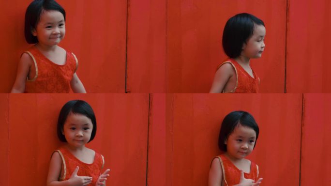 红墙背景上的女婴玩耍无聊倚靠在红色墙壁上