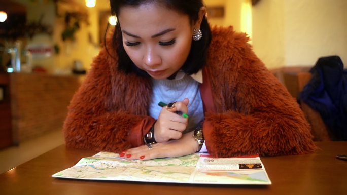 亚洲女游客在咖啡店查看城市地图