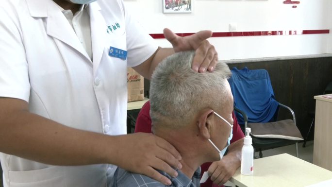 中医按摩医生给老年人按摩颈部治疗颈椎病