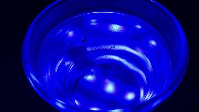 泡腾药丸滴入一杯蓝色的水中并溶解