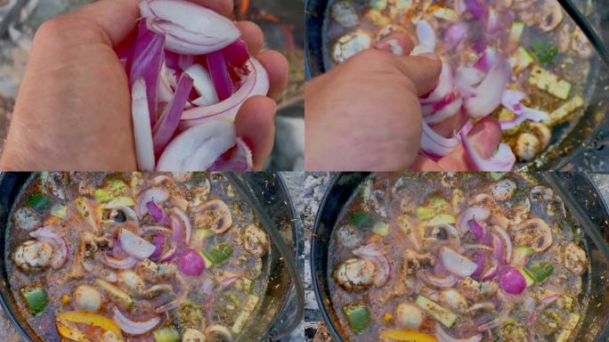POV在篝火上的铸铁锅中向炖菜中加入洋葱的人