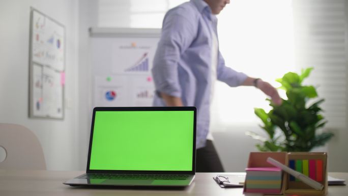 商人在桌上的笔记本电脑绿屏后跳舞