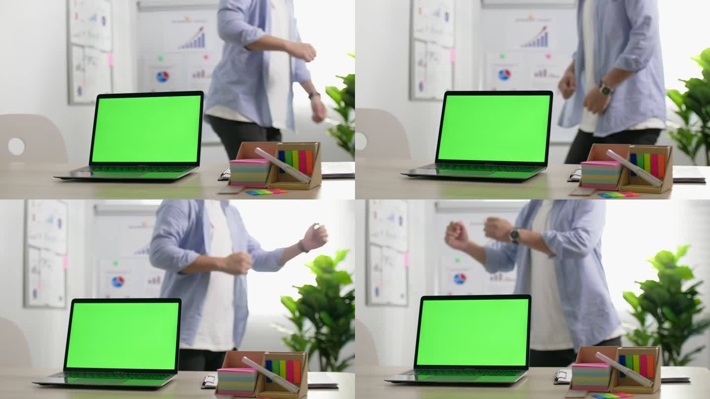 商人在桌上的笔记本电脑绿屏后跳舞