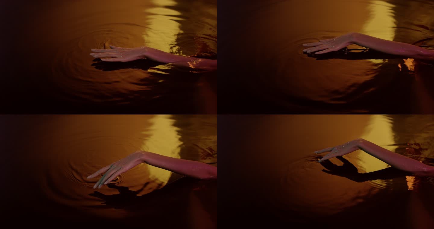 金色光滑的水面。女性手轻轻飞溅并接触液体
