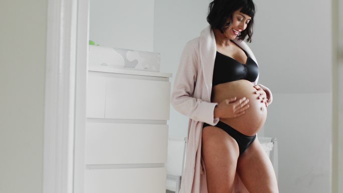 孕妇穿着浴袍站在育婴室