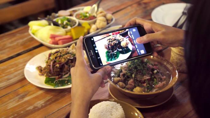 亚洲女性使用手机拍摄泰国食品照片组。