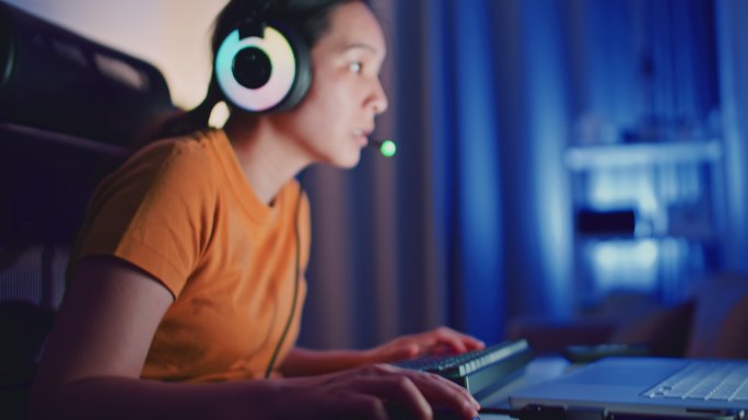 亚洲年轻女子晚上在笔记本电脑上玩电脑游戏