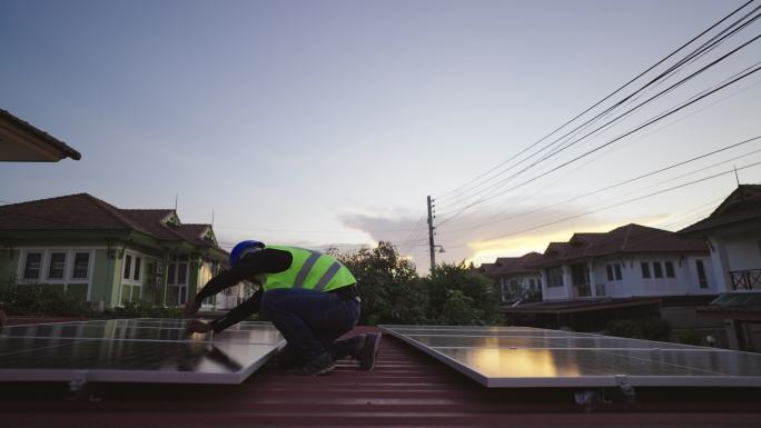 技术工人安装安装在家庭屋顶上的太阳能光伏板。