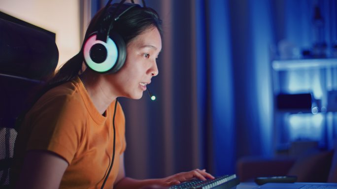 亚洲年轻女子晚上在笔记本电脑上玩电脑游戏