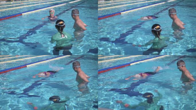 周末上午，亚洲华裔老年女子与退休社区一起在游泳池里向教练学习游泳指导