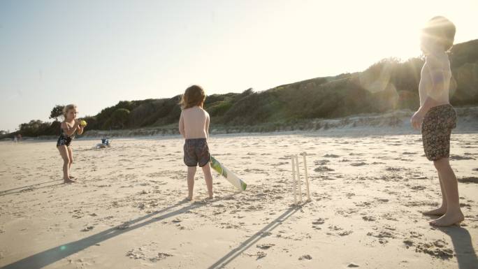 海滩上的板球玩耍母亲指导童年时光
