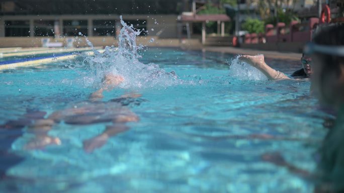 周末上午，一位亚洲华裔老人与退休社区一起在游泳池向教练学习游泳指导