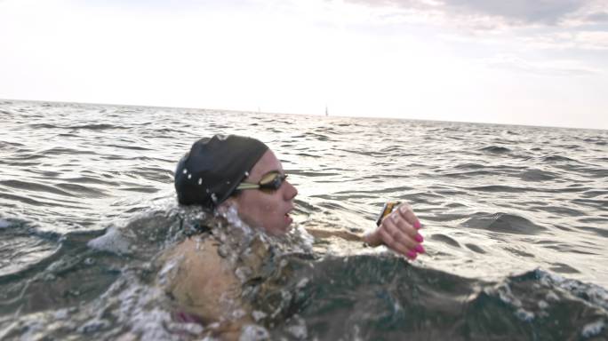 SLO MO女子公开水域游泳运动员在水中停下并检查她的手表
