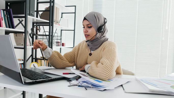 伊斯兰女士在Hijab和耳机在笔记本电脑上进行视频通话