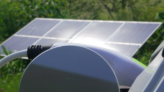 一名妇女在太阳能充电站插上电动汽车插头。