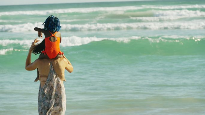 夏日阳光明媚的海洋中，母亲背着女儿