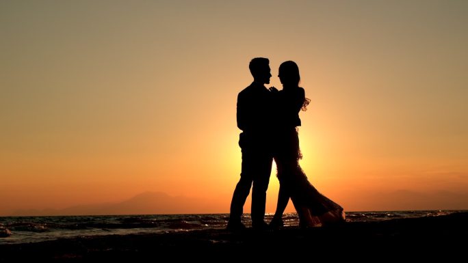 日落时分海滩上一对浪漫情侣的剪影