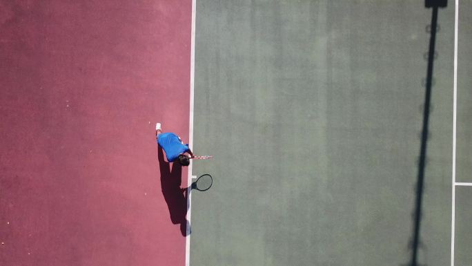 无人机视角亚洲网球运动员发球，阴影正上方