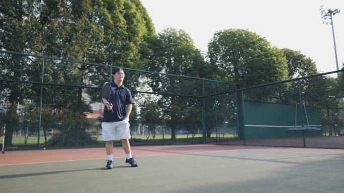 亚洲中国羽绒综合症男子网球运动员周末早晨在网球场练习发球
