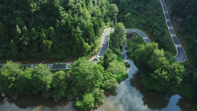 汽车行驶在山上蜿蜒林荫道路上