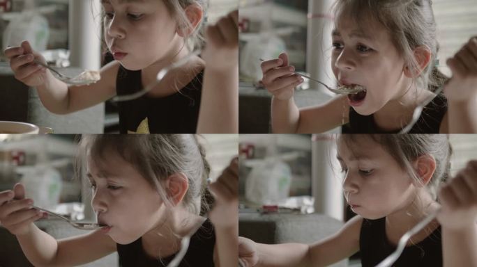 快乐的女孩用勺子吃美味的食物。