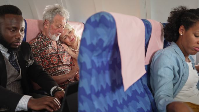 乘飞机旅行时睡在丈夫肩上休息的老年妇女