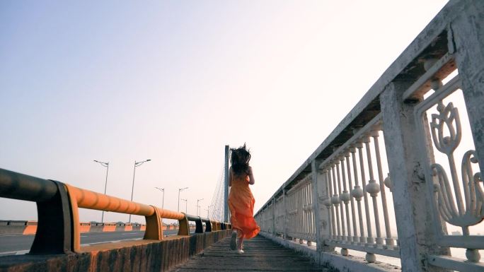 在桥上奔跑着的女孩背影