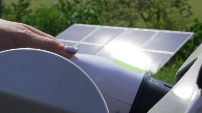 一名妇女在太阳能充电站插上电动汽车插头。